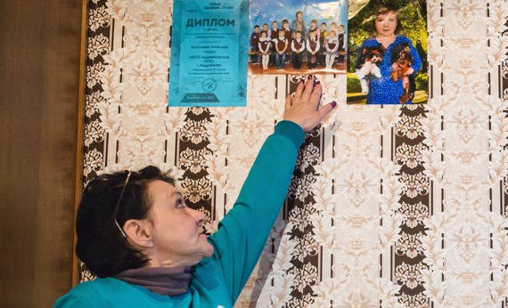 Женщина указывает рукой на фотографии на стене