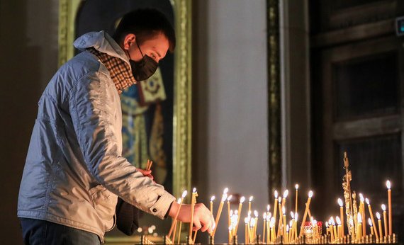 Молодой человек в маске ставит свечу в Казанском кафедральном соборе
