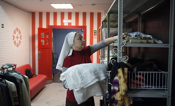 Cестра милосердия в Центре гуманитарной помощи раскладывает чистые вещи
