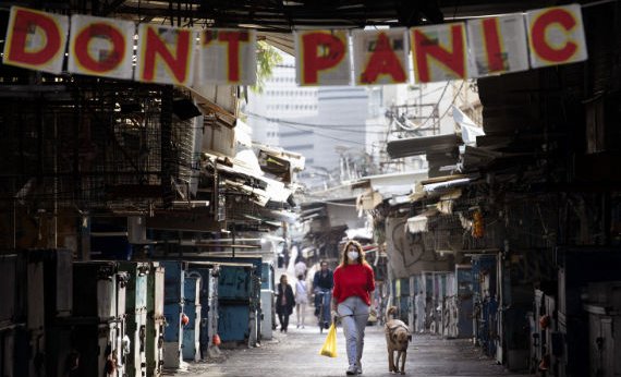 Девушка идет по улице с собакой под плакатом против паники