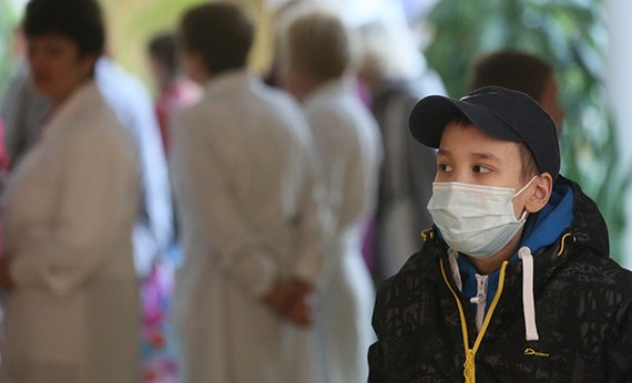 Мальчик в медицинской маске на фоне людей в белых халатах