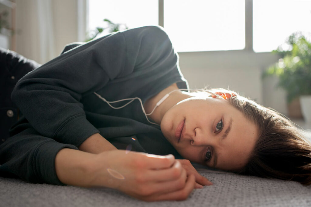 Молодая женщина в наушниках лежит на полу