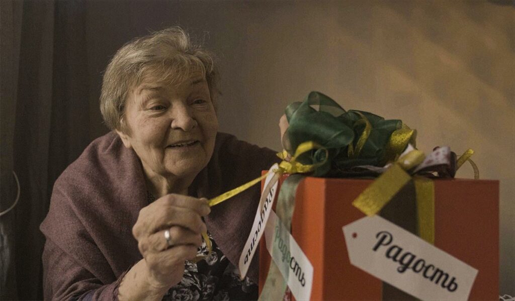 Пожилая женщина распаковывает подарок