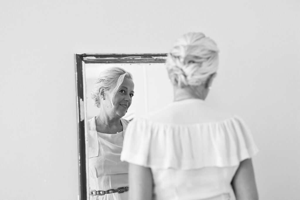 Черно-белая фотография. Татьяна смотрится в зеркало, одета в белое винтажное платье