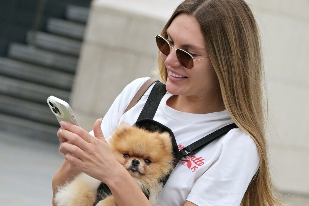 Девушка с собакой породы шпиц на площади возле Павелецкого вокзала в Москве
