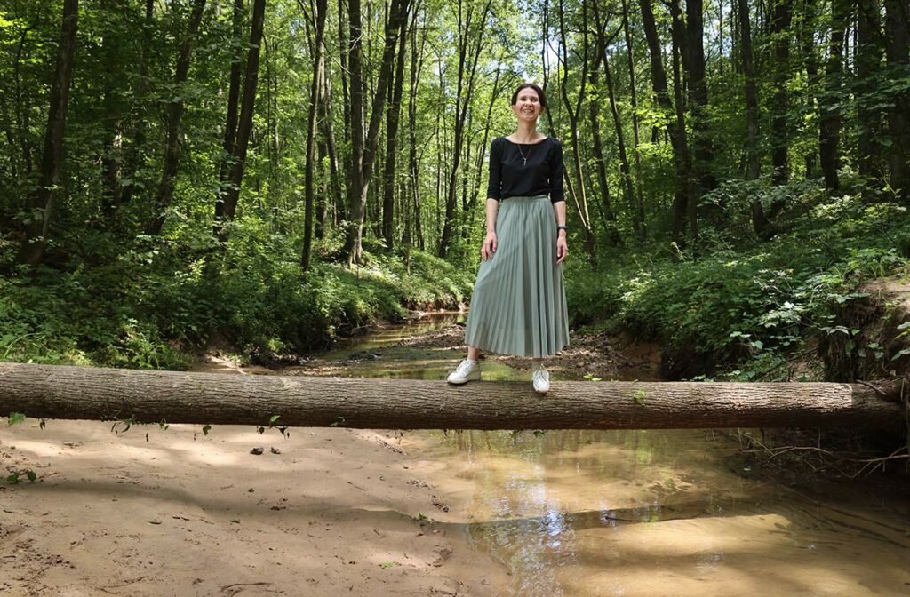 Татьяна Честина стоит на бревне в лесу
