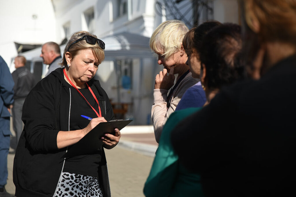 Ольга Петрова выдает прибывающим беженцам номера в очереди. Их люди записывают у себя на руках