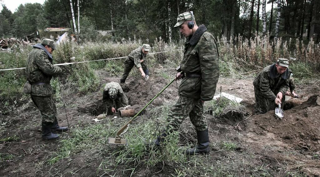 Раскопки солдат времен ВОВ. На переднем плане солдат с миноискателем 