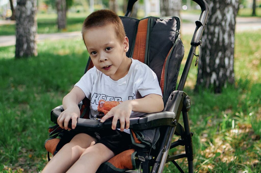 Мальчик в детской инвалидной коляске