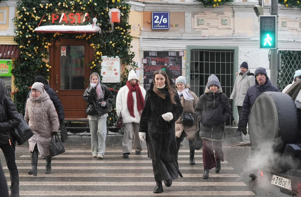 Люди идут по пешеходному переходу, героиня в центре 