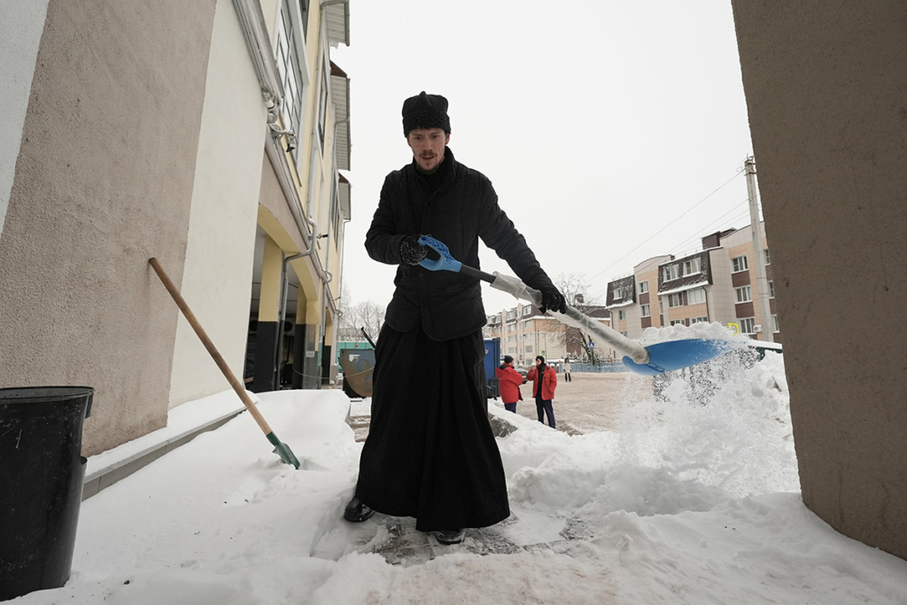 Отец Александр убирает снег